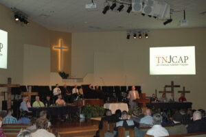 Chief C.J. Ball speaks to an audience of about 100 at Lincoln Avenue Baptist Church. Flanked by nine graduates of the JCAP program on either side, and six in the back, Ball acknowledged the achievements and hard work of the men who are now leaving his jail. James K. Galloway